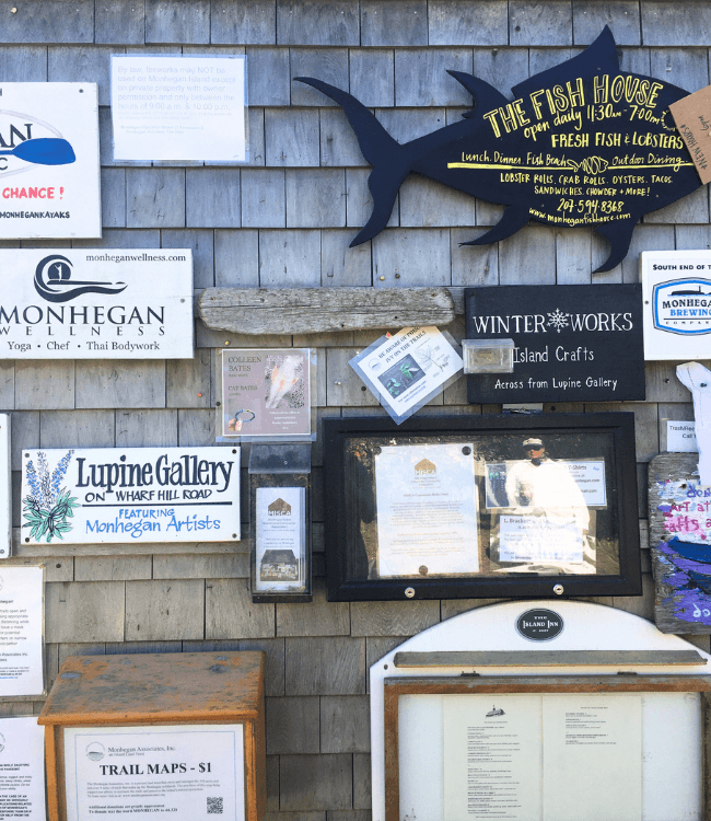 A weathered bulletin board displaying various business advertisements and event announcements on Monhegan Island.