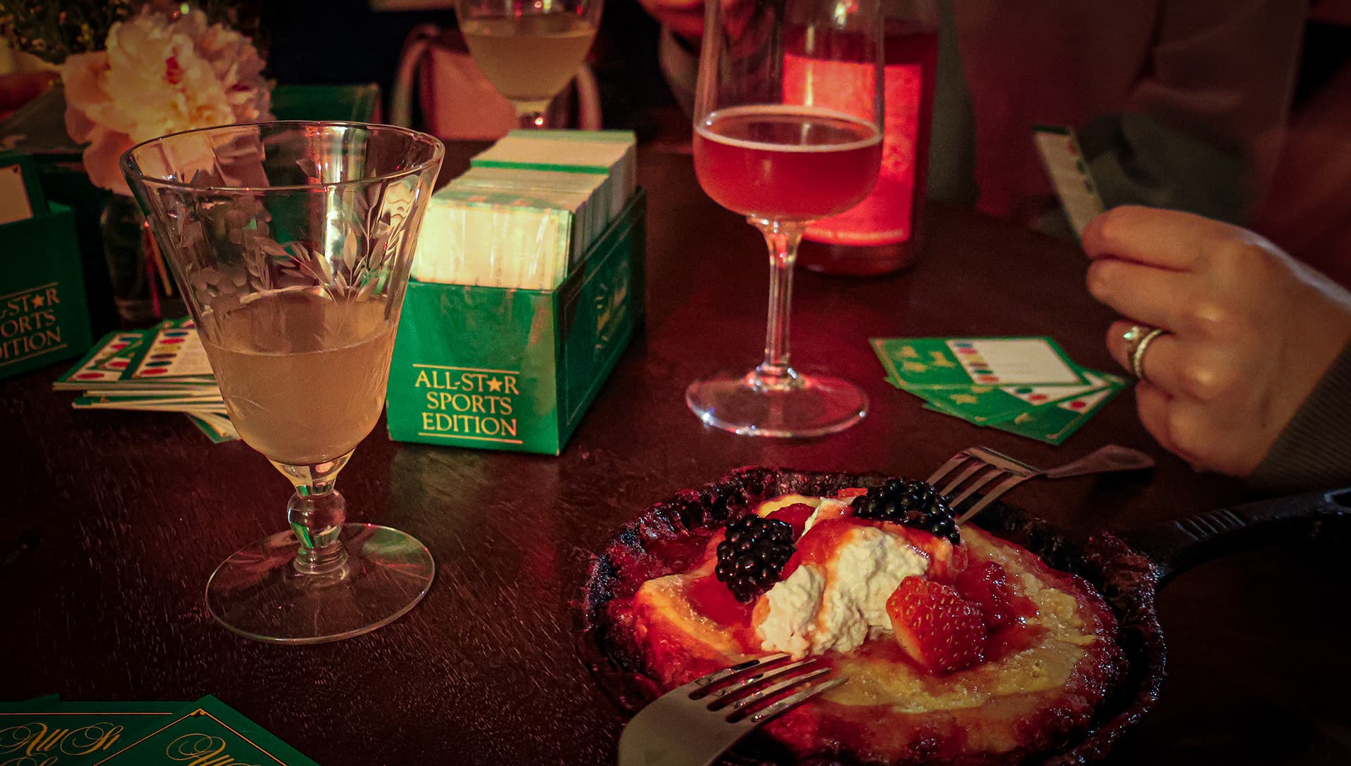 A table is set with drinks and a dessert topped with berries and cream.
