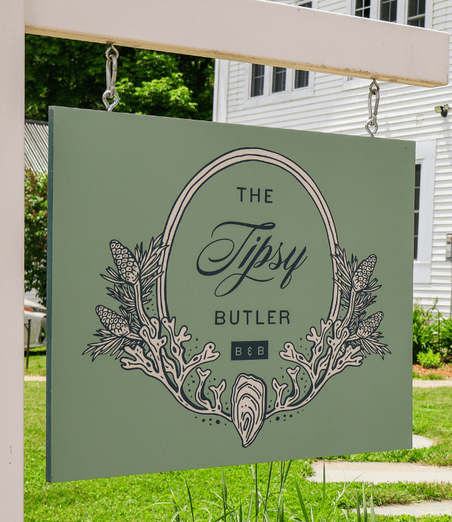 A sign for "The Tipsy Butler B&B" featuring decorative elements.